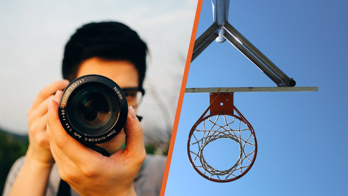 Un fotógrafo enfoca con su cámara junto a un aro de baloncesto visto desde abajo contra el cielo azul.