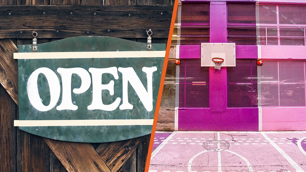 Un cartel de «Open» colgado en una puerta de madera junto a una canasta de baloncesto en una pista callejera pintada de rosa y morado.